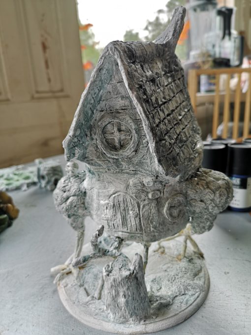 Work in Progress of Baba Yaga Chicken Hut. Sat on a table with a layer of black wash over the grey clay.