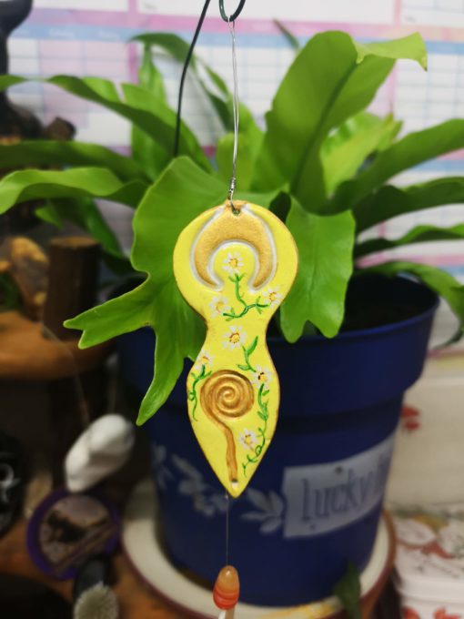 Yellow flower Goddess plant companion, shown in a blue plant pot on a wooden alter.