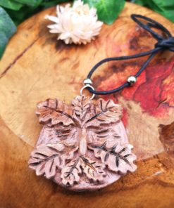 Terracotta greenman necklace on a curved piece of wood