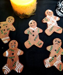 5 zombie clay gingerbread man on a black background with a candle and skull decoration.